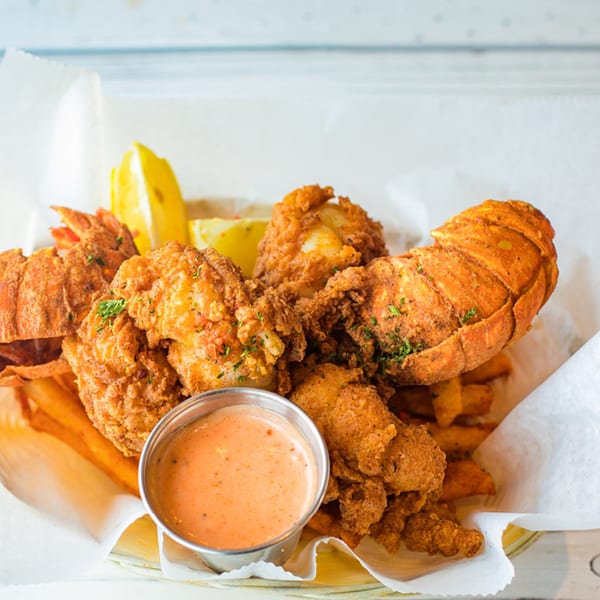 Ben's Crab fried lobster tails and shrimp with fries, lemon wedges, and dipping sauce.