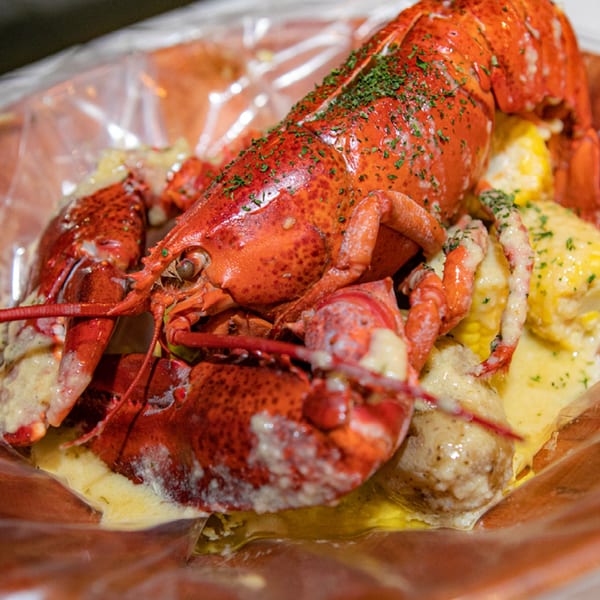 Ben's Crab's whole red lobster, corn, and potatoes covered in creamy sauce and parsley.
