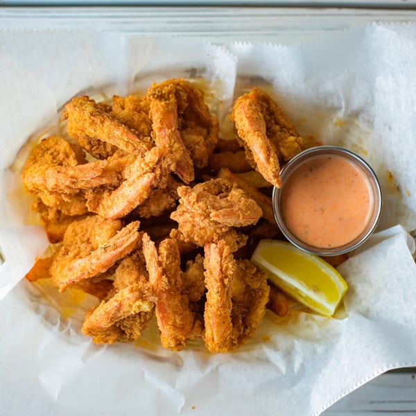 Ben's Crab fried shrimp and fries in a basket with dipping sauce and a lemon wedge.