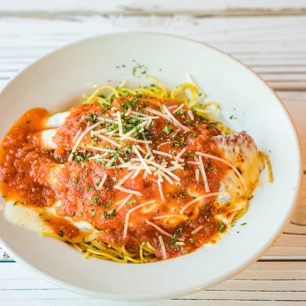 Ben's Crab seafood pasta dish with red sauce, melted cheese, and fresh herbs.