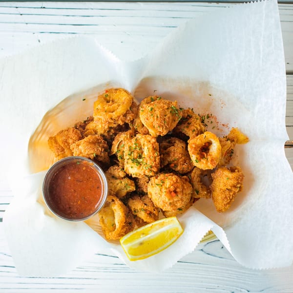 Ben's Crab fried calamari with a side of red dipping sauce and a lemon wedge.