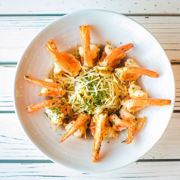 Ben's Crab shrimp scampi with pasta, parmesan, and parsley in a white bowl.