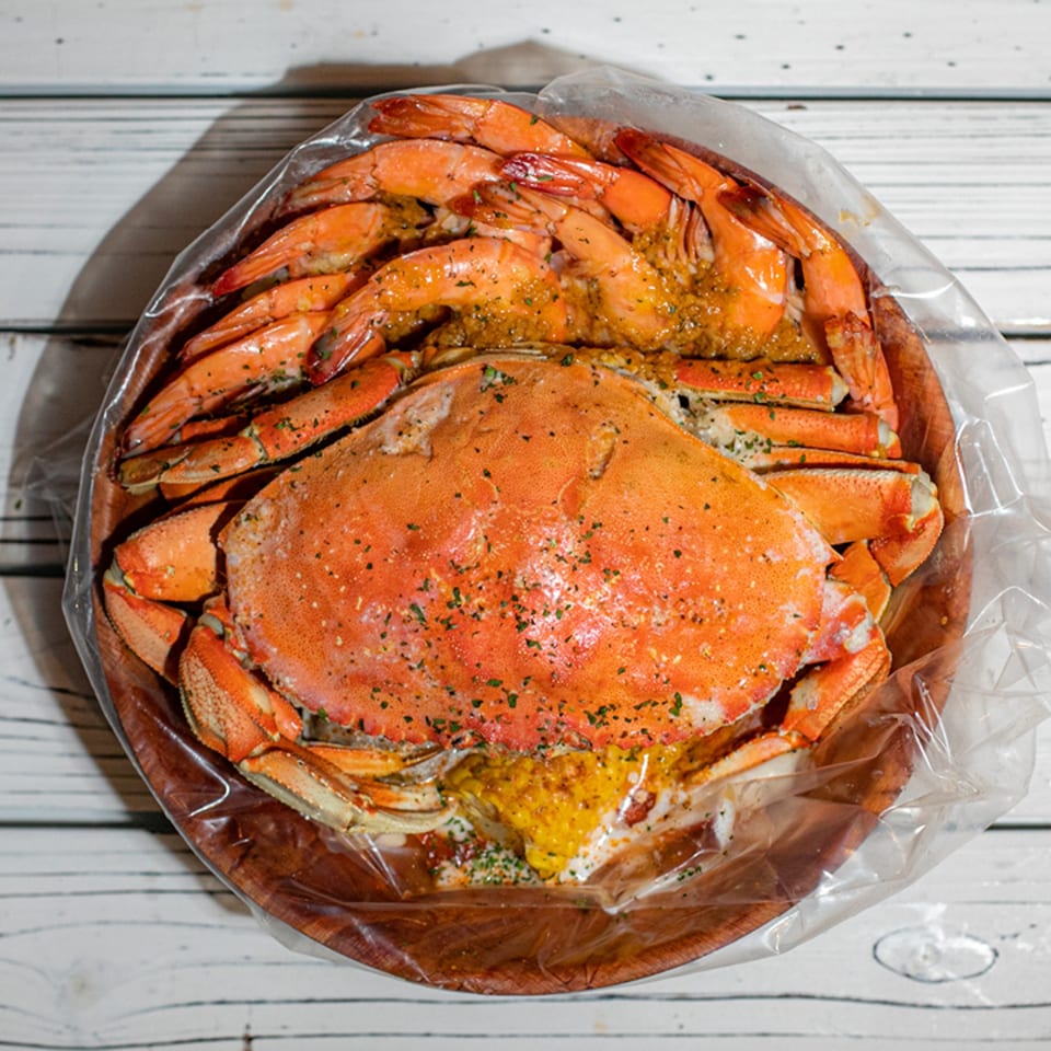 Ben's Crab seafood boil with a large crab and shrimp in a clear bag.
