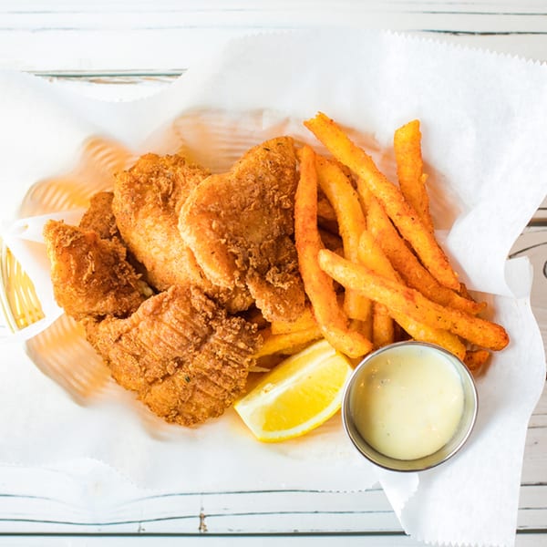 Ben's Crab fried fish and seasoned fries in a basket with lemon and dipping sauce.