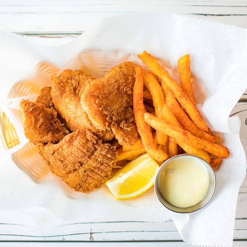 Ben's Crab fried fish and seasoned fries in a basket with lemon and dipping sauce.