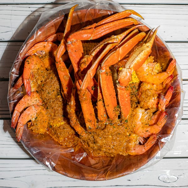 Ben's Crab seafood boil with snow crab legs, shrimp, and corn in a spicy sauce.