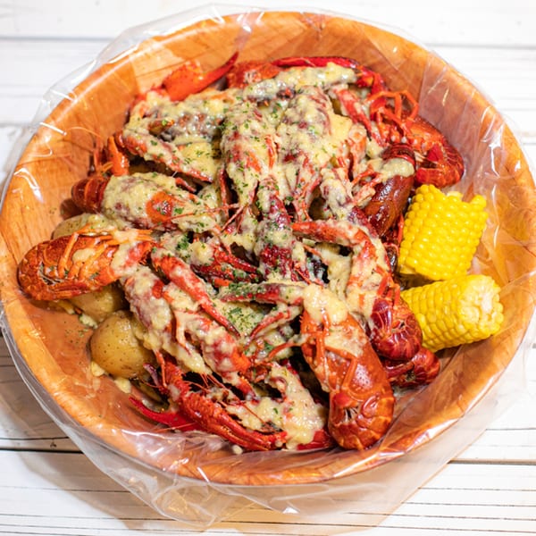Ben's Crab seafood boil with crawfish, potatoes, and corn on the cob, topped with cheese and herbs.