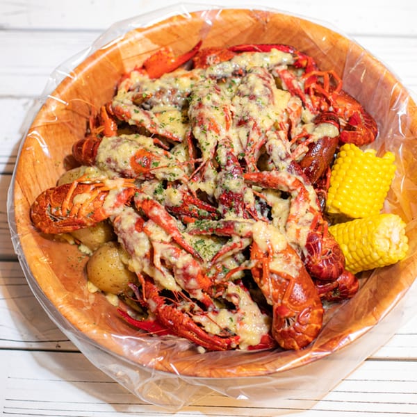 Ben's Crab seafood boil with crawfish, potatoes, and corn on the cob, topped with melted cheese.
