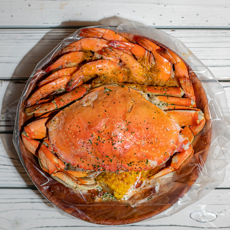 A Ben's Crab seafood boil with a whole crab and shrimp in a plastic bag.