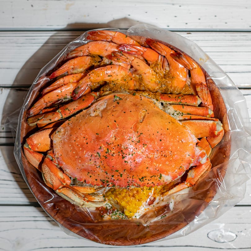 A Ben's Crab seafood boil with a whole crab and shrimp in a plastic bag.